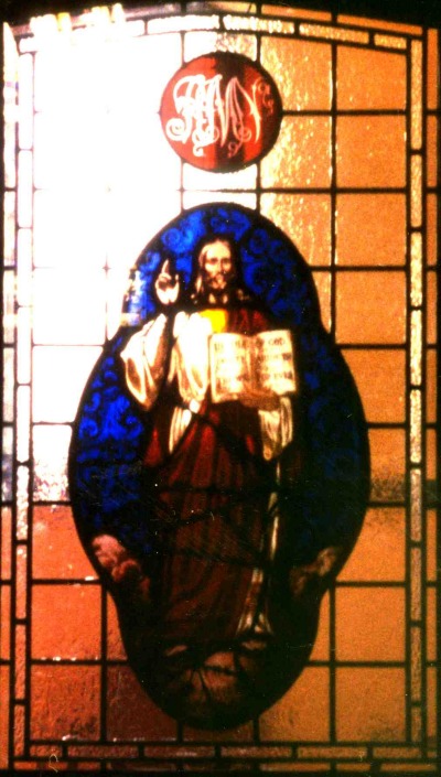 Photo of window in vestry door, Jesus holding a book against a red background